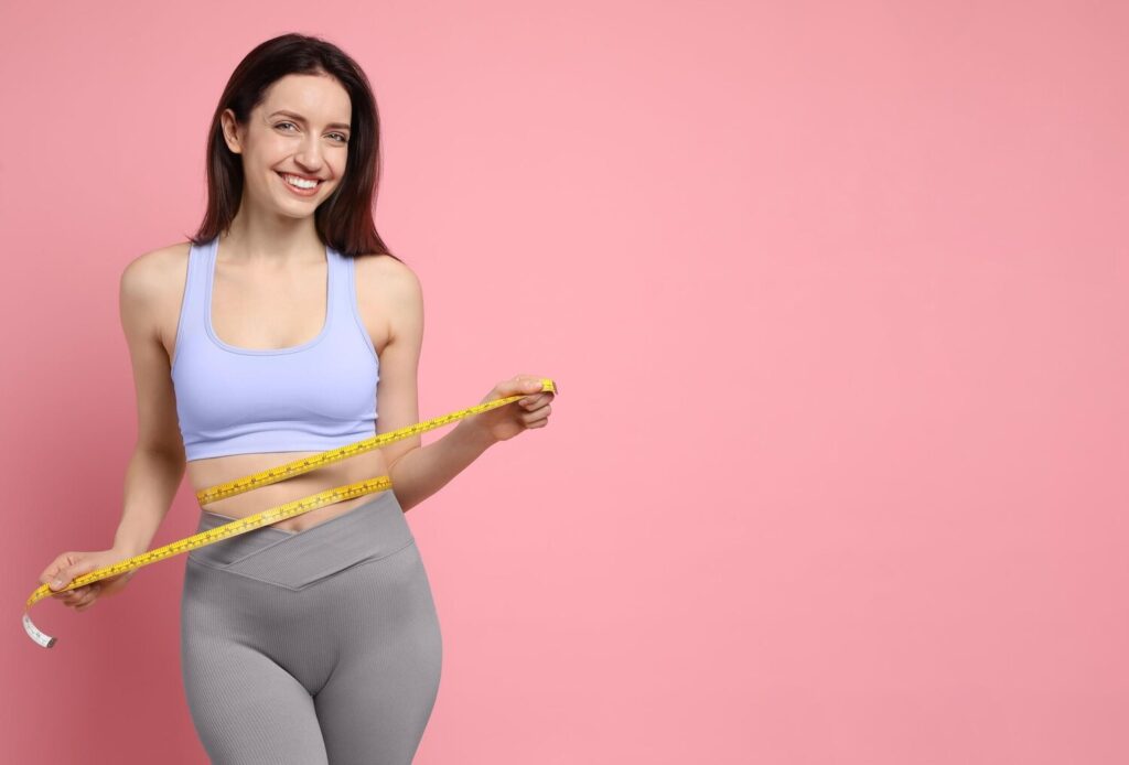 happy young woman with measuring tape showing her slim body pink background space text 495423 82329
