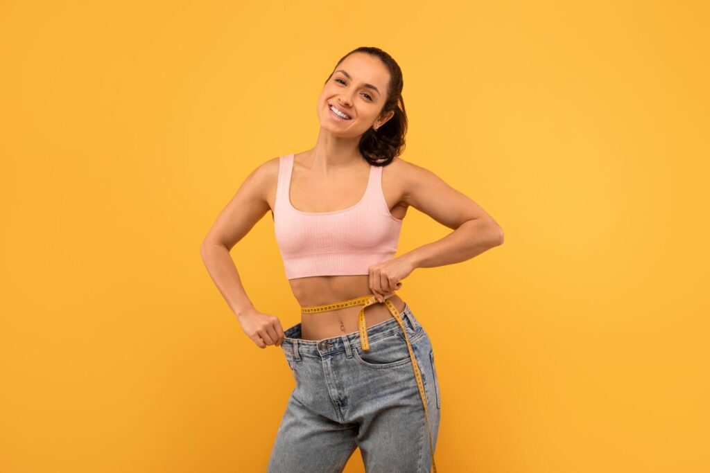 fit young woman celebrating weight loss by holding oversized jeans 116547 111349